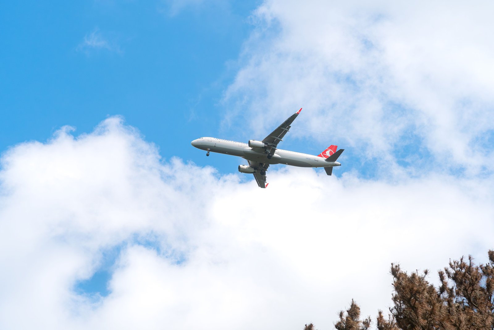 A commercial airplane glides through a clear blue sky with scattered clouds, capturing the essence of aviation travel.